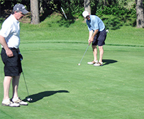 NEGT Advisory Board Member, Jim Whitney, focuses on the line of his putt at Marlborough's tricky 15th green, as NEGT Tournament Operations Manager, Greg Labutis, stands by.